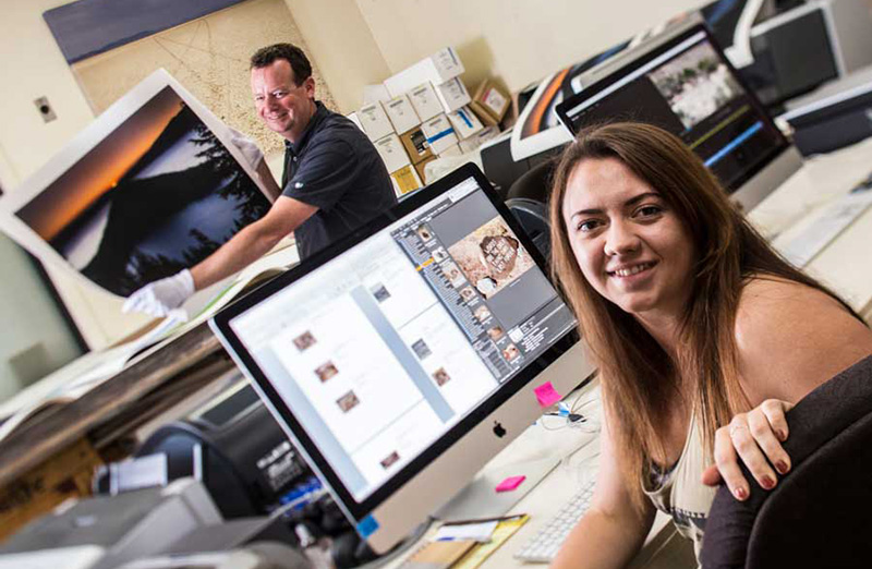 A Graphic designer sitting in-front of their computer smiling