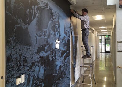 Man on ladder installing wall vinyl